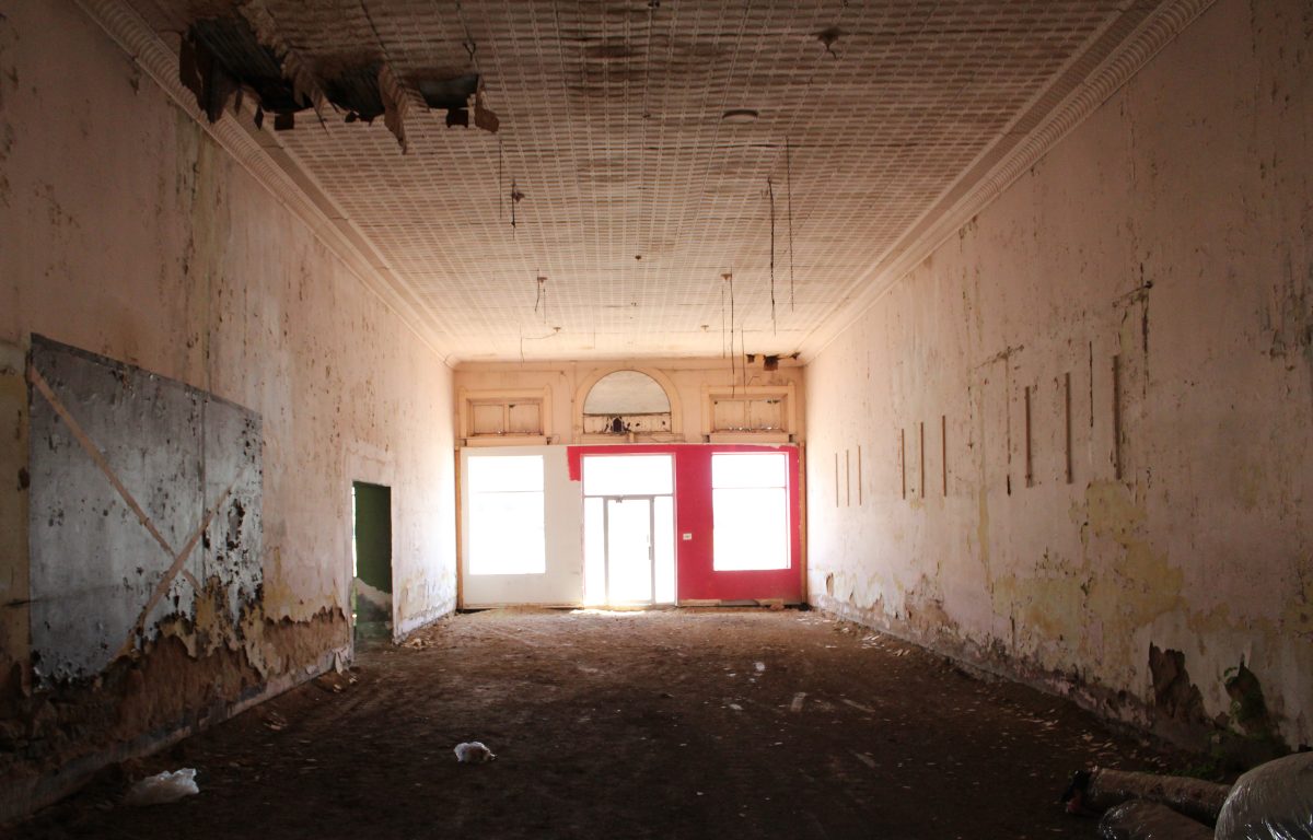 The peeling interior of an abandoned storefront with bright red doors