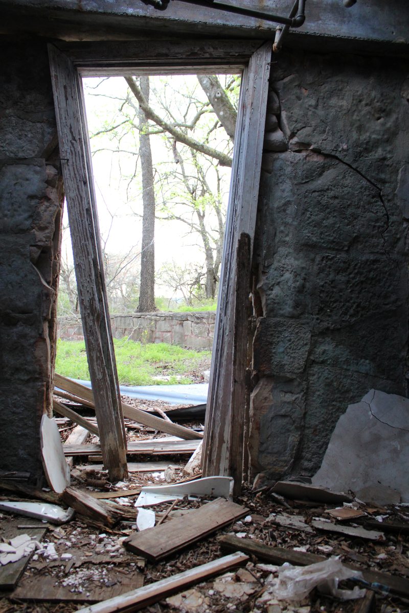 A ruined stone doorway opening onto bare trees, debris across the floor