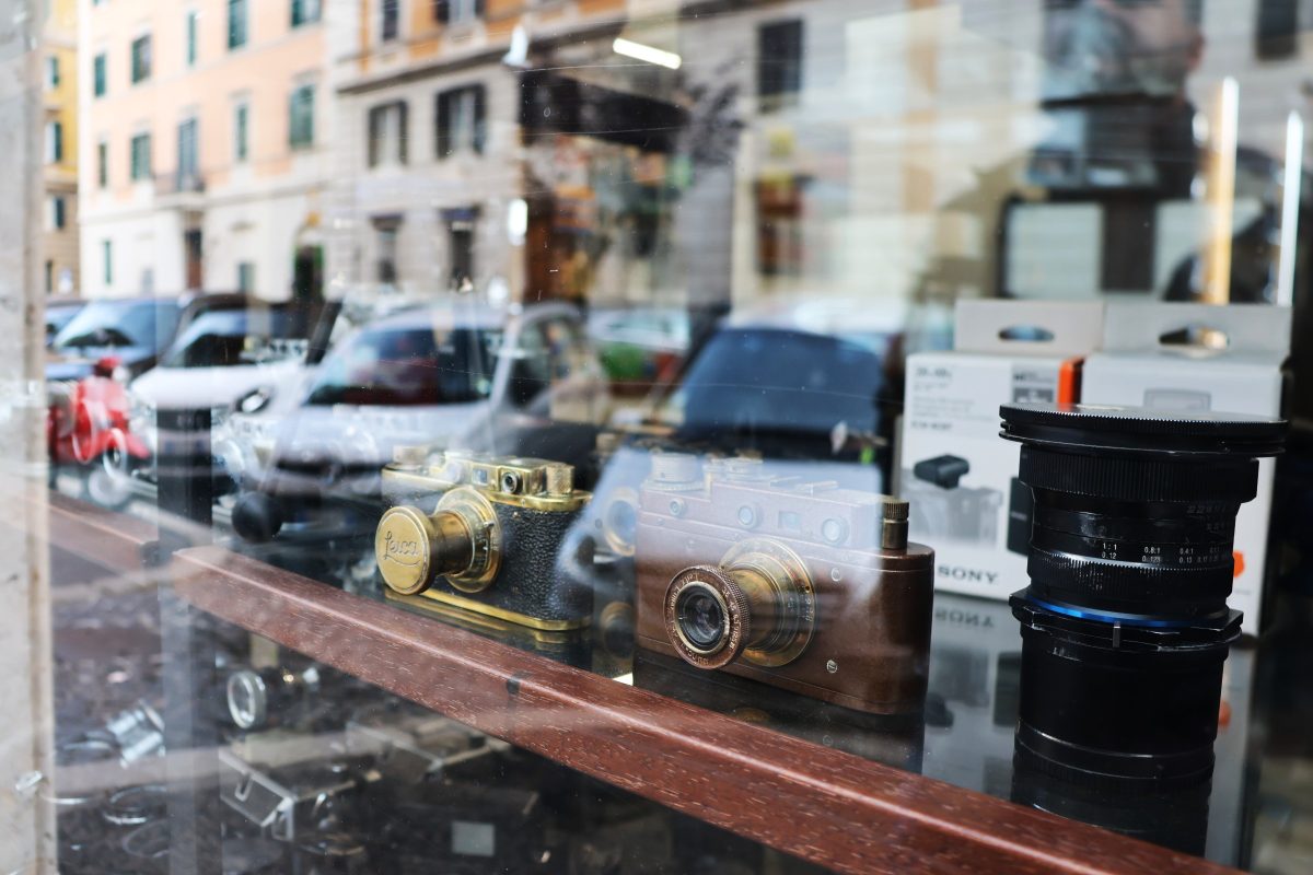 Vintage cameras in a shop window, the street reflected in the glass